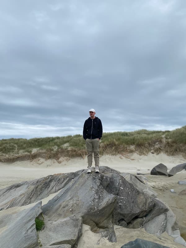 Fabi beim Hellestrostranden Norwegen auf einem Felsen
